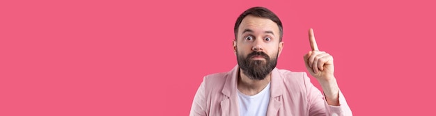 Bel homme avec une barbe dans une veste rose réfléchit sur un fond rouge isolé