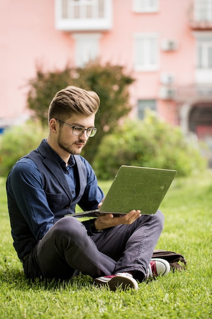 Bel Homme Avec Une Barbe Est Assis Sur Une Pelouse Et Travaille Sur Un Ordinateur Portable