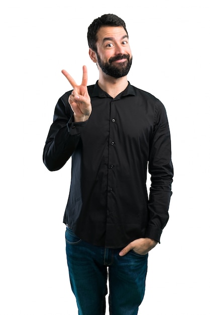 Bel homme avec la barbe faisant le geste de la victoire sur fond blanc