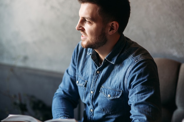 Bel homme avec une barbe en lisant un livre dans un café.