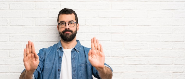 Bel Homme à La Barbe Sur Mur De Briques Blanches Faisant Arrêt Geste Et Déçu