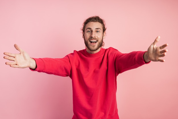 Bel homme avec une barbe portant des vêtements décontractés, regardant la caméra, souriant à bras ouverts.