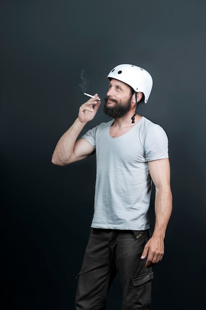 Bel homme barbu américain dans un casque de vélo. arrêter de fumer. Russian Man Smoking Cigarette après un entraînement intensif à vélo. Sport et habitude nuisible. Personne active appréciant les moments de la vie quotidienne