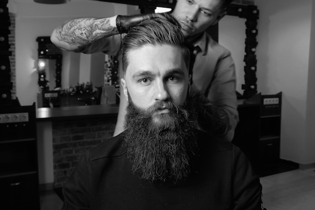 Un bel homme barbu attend un salon de coiffure avec impatience