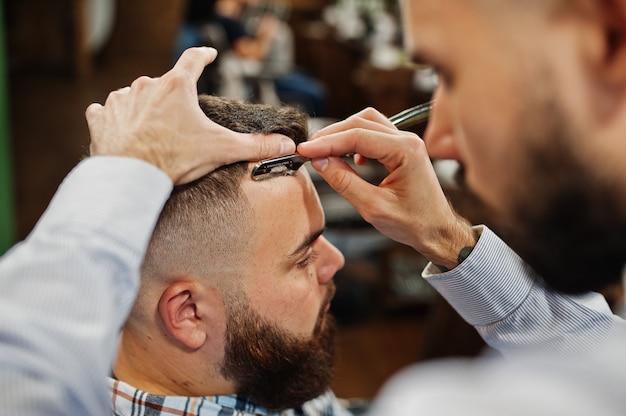 Bel homme barbu au salon de coiffure, coiffeur au travail.