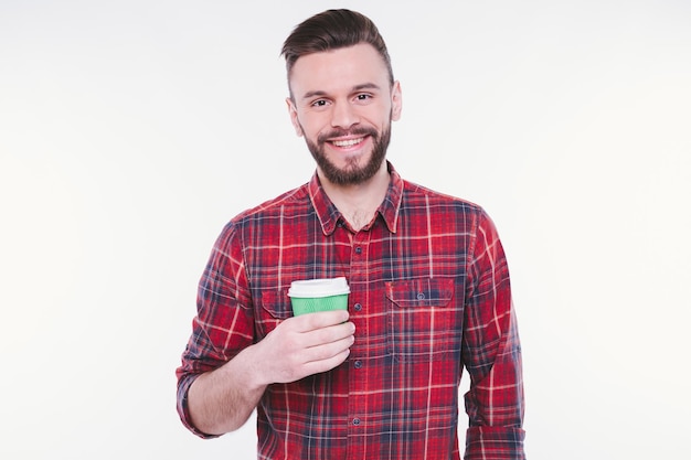 Bel homme barbu boit du café dans une tasse en papier Café à emporter Concept de café Café Bonjour Un gars heureux savoure du thé chaud frais Un barista souriant vous offre une boisson