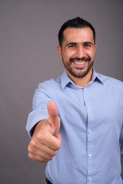 Bel homme barbu contre le mur gris