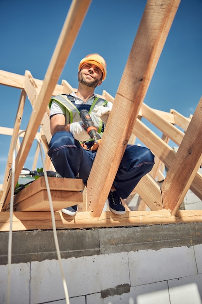 Bel homme barbu gardant le sourire sur son visage tout en profitant du beau temps pendant le travail