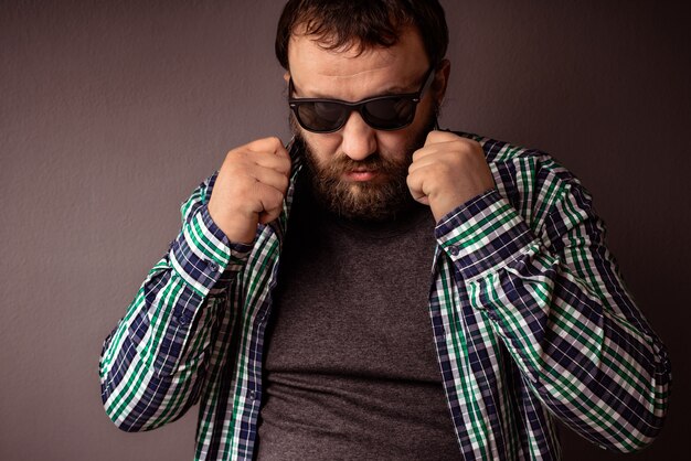 Bel homme barbu hipster avec des lunettes de soleil et un col de chemise.