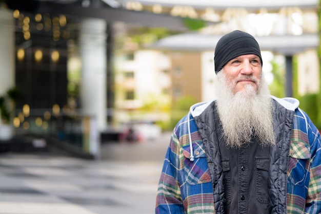 Bel homme barbu mature pensant dans les rues de la ville