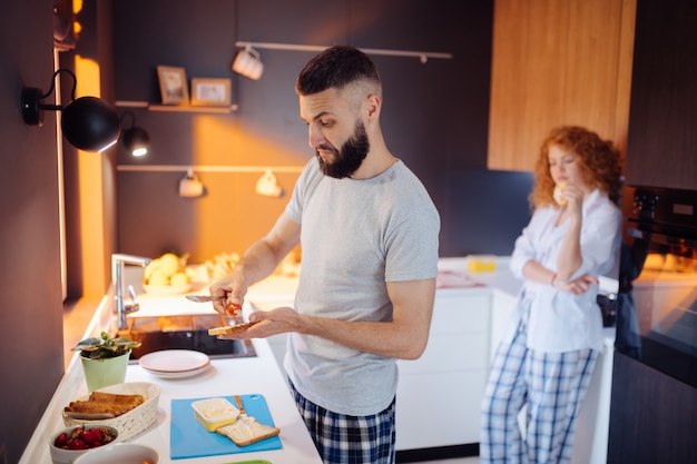 Bel homme barbu mettant la tomate sur le sandwich