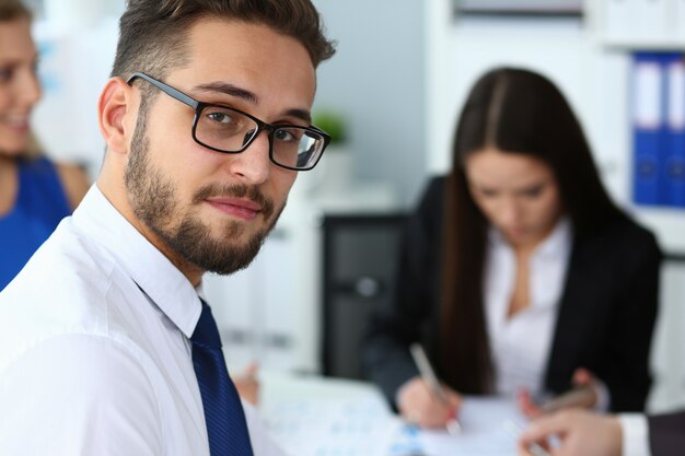 Bel homme barbu souriant travaillant avec des collègues au bureau