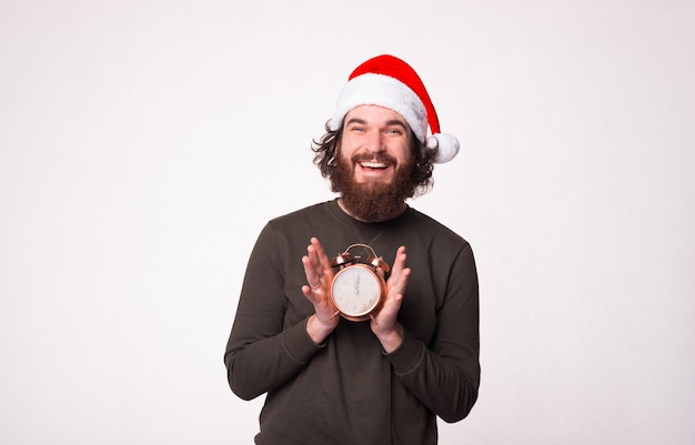 Bel Homme Barbu Sourit Et Montre Que C'est L'heure De Noël Sur Un Réveil