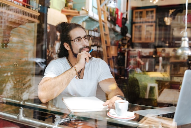 Bel homme barbu tenant un stylo tout en étant prêt à écrire