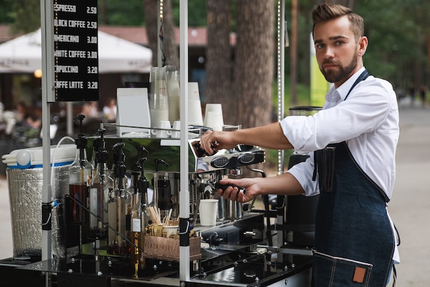 Bel homme barista pendant le travail dans son café de la rue mobile