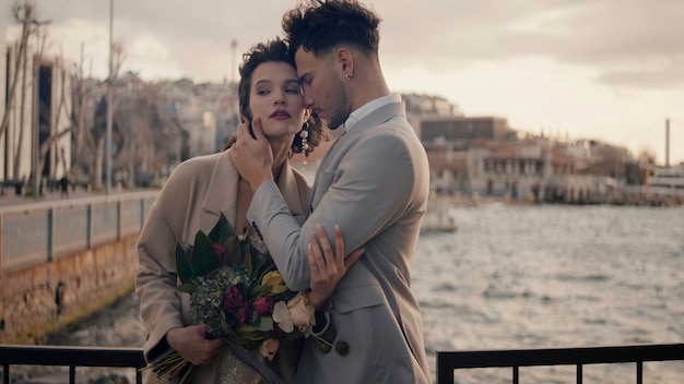 Un bel homme et une belle femme à un rendez-vous près de la rivière debout sur le pont un jour venteux