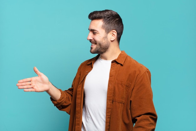 Bel homme blond adulte souriant vous saluant et vous offrant une poignée de main pour conclure un concept de coopération réussi