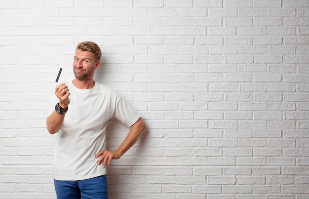 Bel homme blond avec une carte de crédit sur un mur de grunge