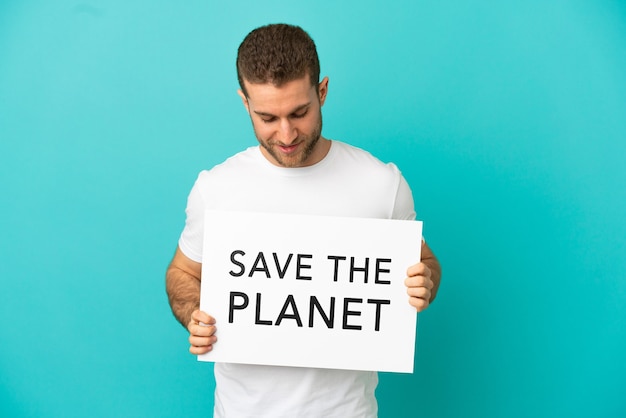 Bel homme blond sur fond bleu isolé tenant une pancarte avec texte Save the Planet