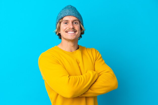 Bel homme blond isolé sur un mur bleu avec les bras croisés et impatient