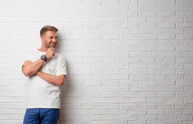 Bel homme blond pensant contre un mur grunge