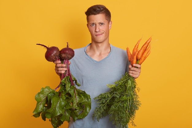 Photo bel homme blond tenant des légumes frais dans les mains