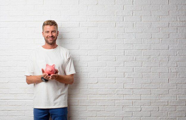 Bel homme blond avec une tirelire sur un mur de grunge