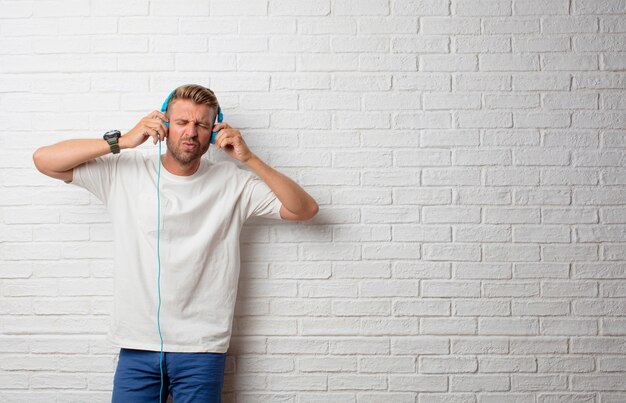 Bel homme blonde écoute de la musique avec un casque