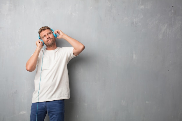 Bel homme blonde écoute de la musique avec un casque