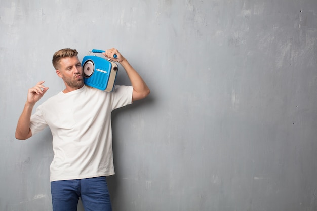 Bel homme blonde écoute la musique avec une radio vintage