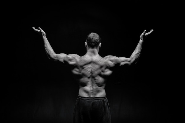 Bel homme bodybuilder ou mec musclé sexy avec corps d'athlète et entraînement du dos et pose, noir et blanc