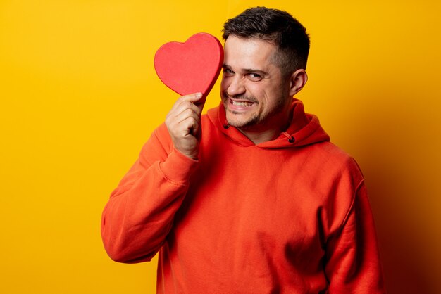 Bel homme avec boîte forme coeur sur mur jaune