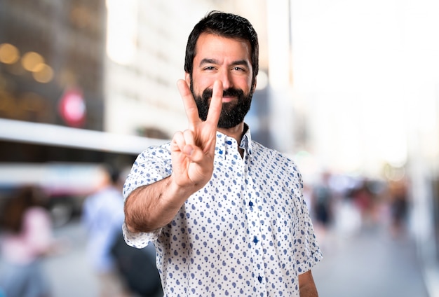 Bel homme brune avec une barbe comptant deux