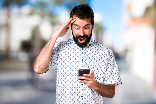 Bel homme brune avec une barbe parlant au mobile