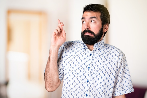 Bel homme brune avec une barbe avec ses doigts traversant