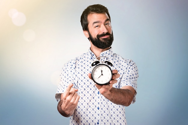 Bel homme brune avec une barbe tenant une horloge vintage