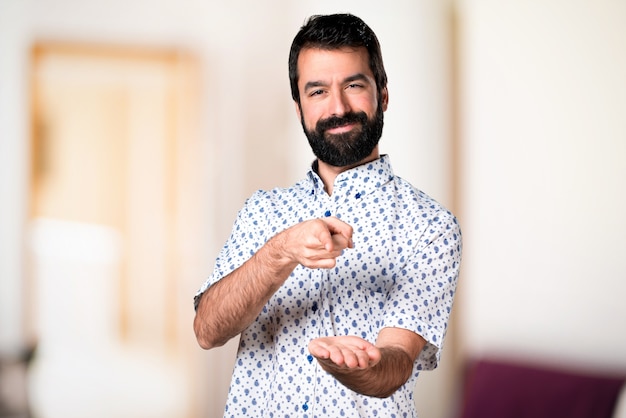 Bel homme brune avec une barbe tenant quelque chose