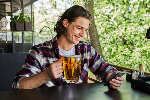 Bel homme buvant de la bière sur la terrasse du café d'été.