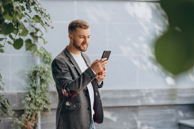 Bel homme buvant du café et utilisant le téléphone