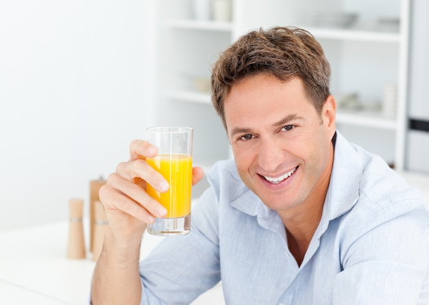 Bel homme buvant un jus d&#39;orange dans la cuisine