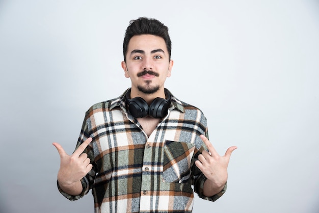 bel homme avec un casque posant sur un mur blanc.