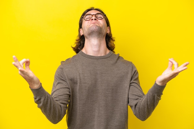 Bel homme caucasien isolé sur fond jaune dans une pose zen