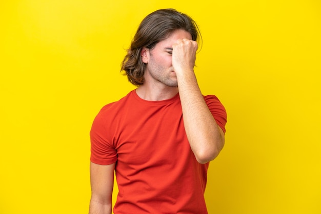 Bel homme caucasien isolé sur fond jaune avec maux de tête