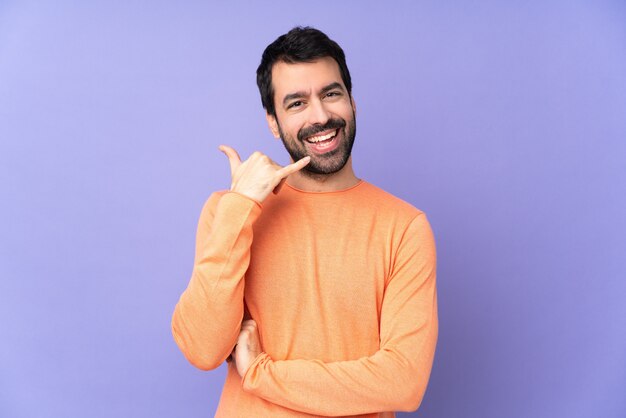 Bel homme caucasien sur mur violet isolé, faisant le geste du téléphone. Rappelez-moi signe