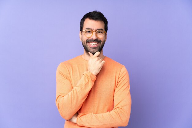 Bel homme caucasien sur mur violet avec des lunettes et souriant