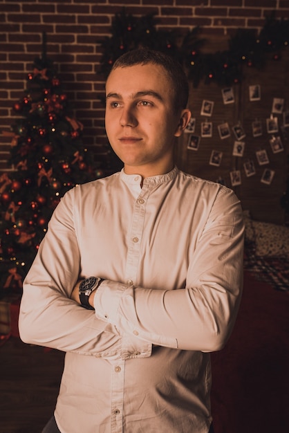 Photo bel homme célébrant le nouvel an et noël à l'arbre de noël décoré et des guirlandes