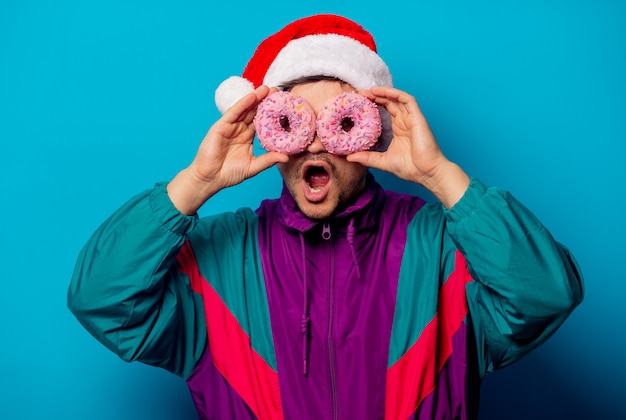 Bel homme en chapeau de Noël et veste des années 90 avec des beignets