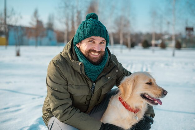 Photo bel homme avec un chien golden retriever à pied dans la prairie de printemps