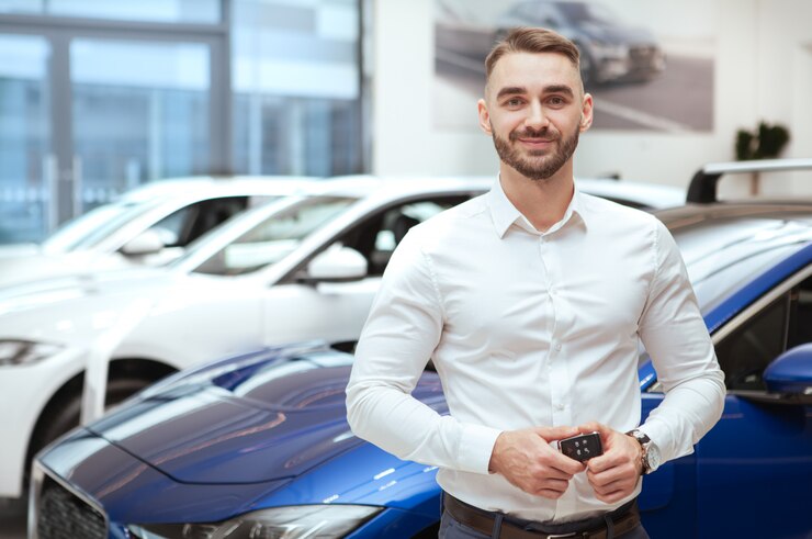 Bel homme choisissant une nouvelle automobile chez le concessionnaire