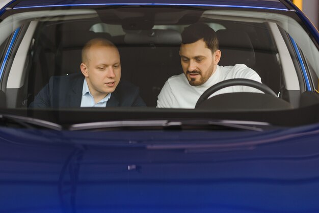 Bel homme choisissant une voiture dans une salle d'exposition